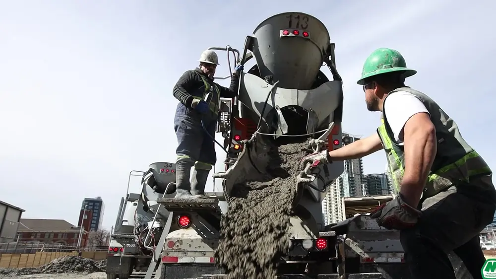 A crew in hi-vis pours concrete from a chute