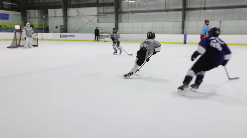 Two players race up the ice at a hockey academy practice
